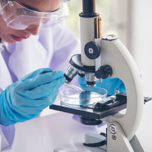 Woman scientist in lab look at science microscope medical test a