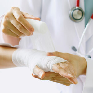 Close-up of female doctor with stethoscope bandaging hand of pat