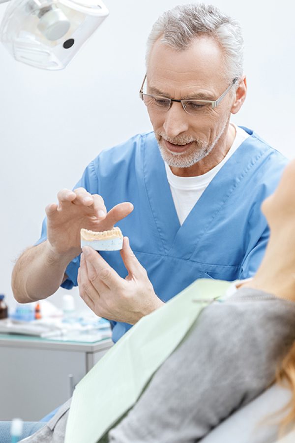 dentist showing jaws model to patient in dental clinic